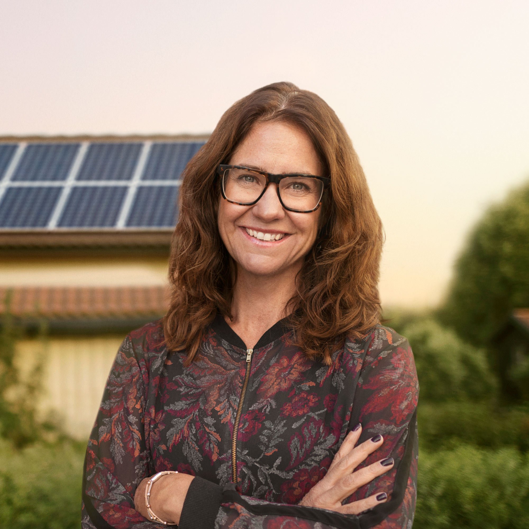 Kvinna står framför hus med solpaneler